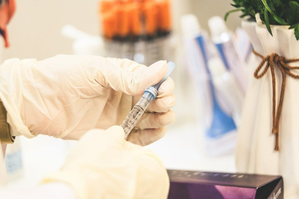 Gloved hand preparing syringe for injection