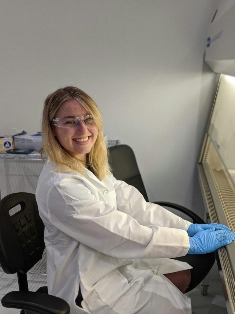 Scientist in lab coat wearing safety glasses.