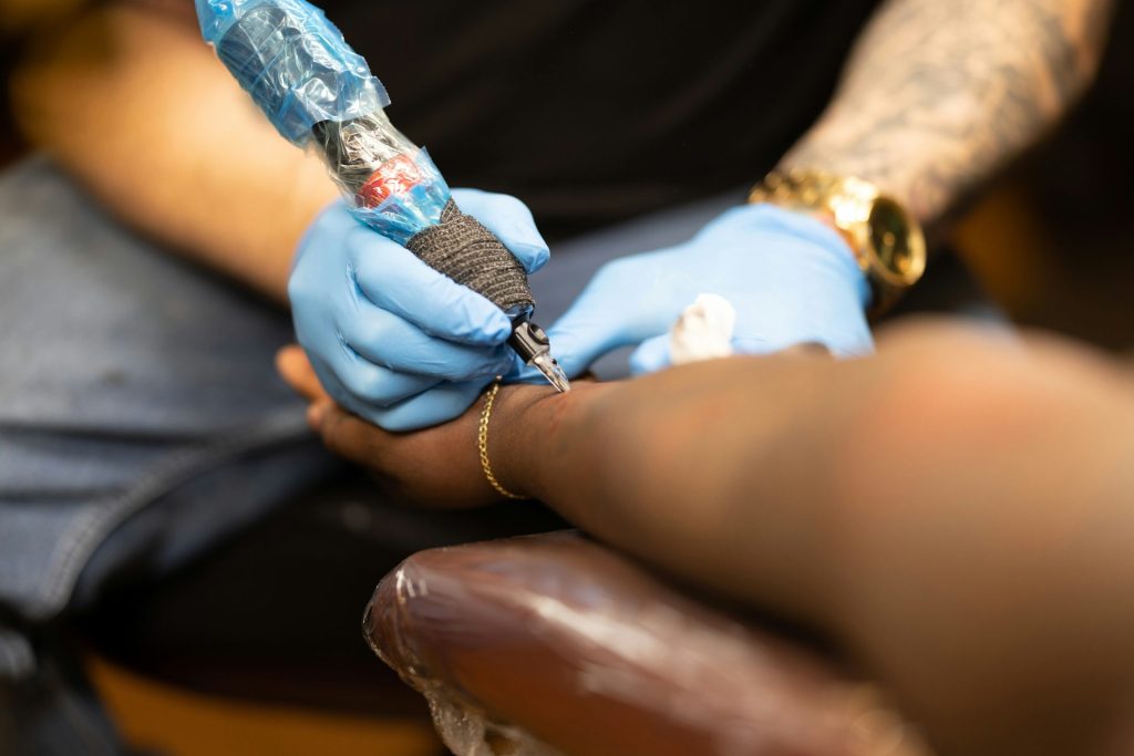 Tattoo artist working on client’s arm